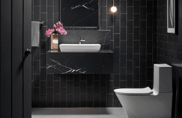 Lake Forest Plumber sink and toilet in a modern bathroom with vertically-oriented rectangular black tile with light gray grout, a black quartz wall-hung vanity
