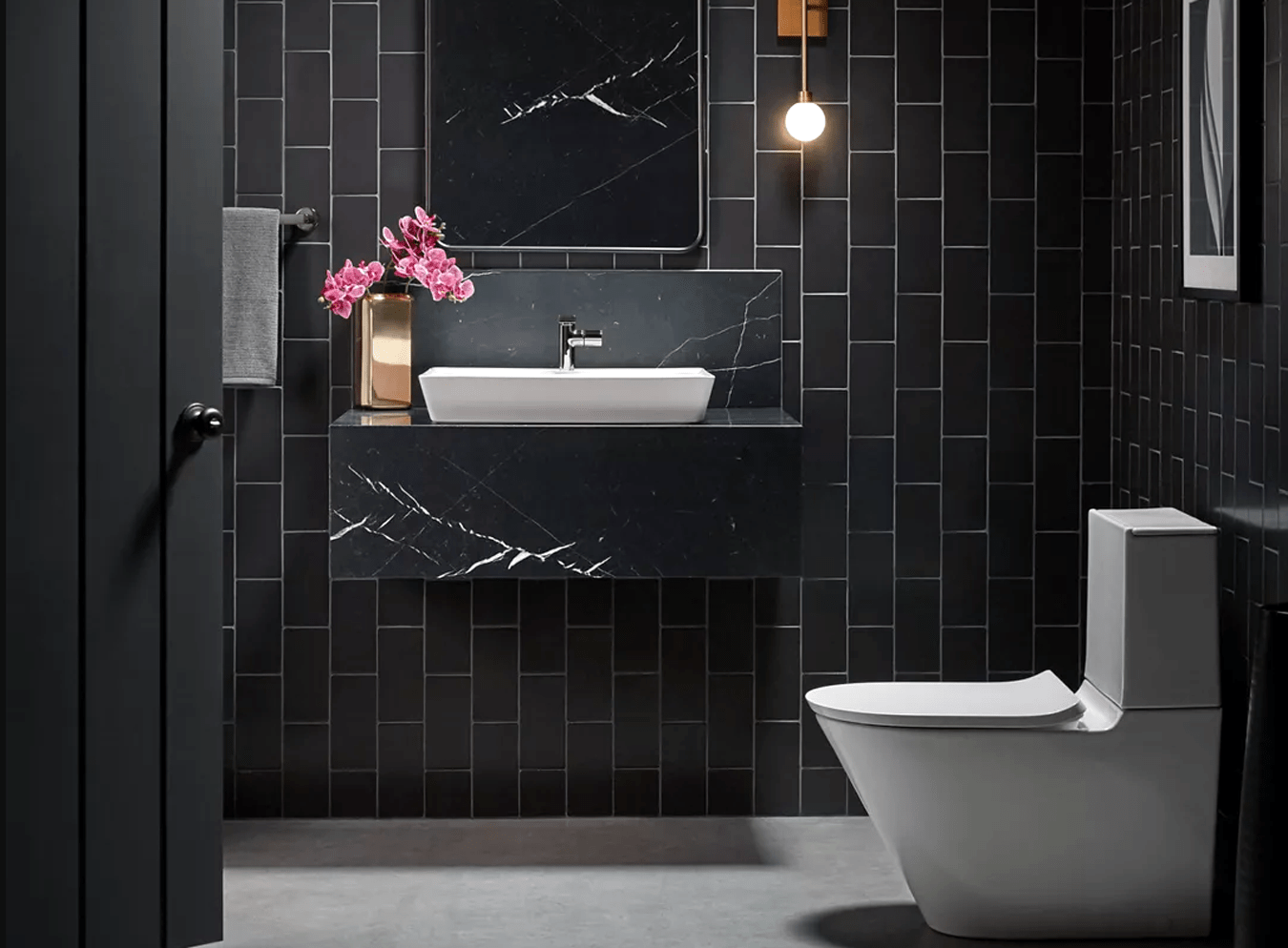 Lake Forest Plumber sink and toilet in a modern bathroom with vertically-oriented rectangular black tile with light gray grout, a black quartz wall-hung vanity
